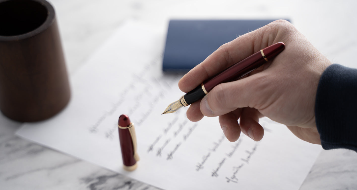 Man writing with a black ballpoint pen in notebook