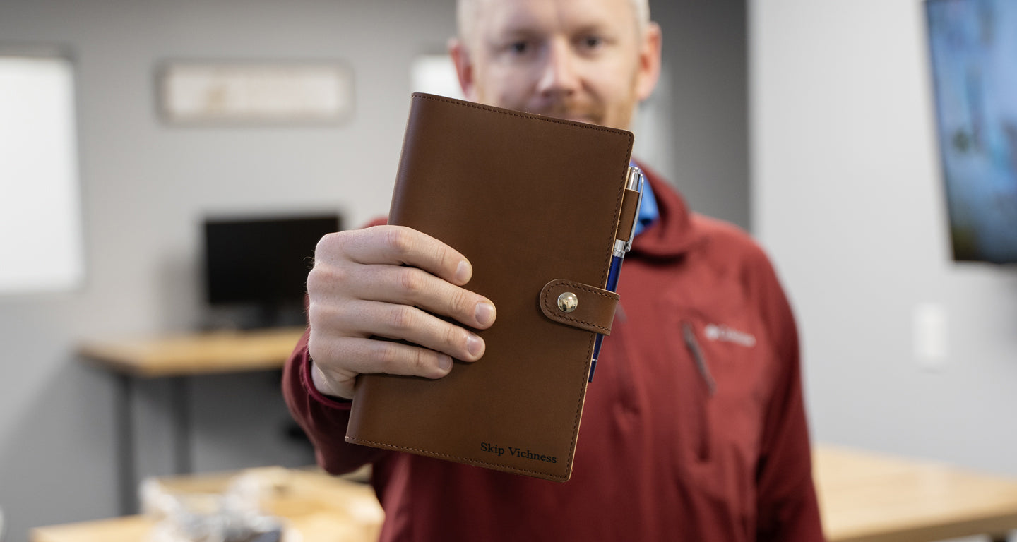 A Man holding Noteworthy Leather Journal Custom Engraved with an Abingdon Blue Rollerball