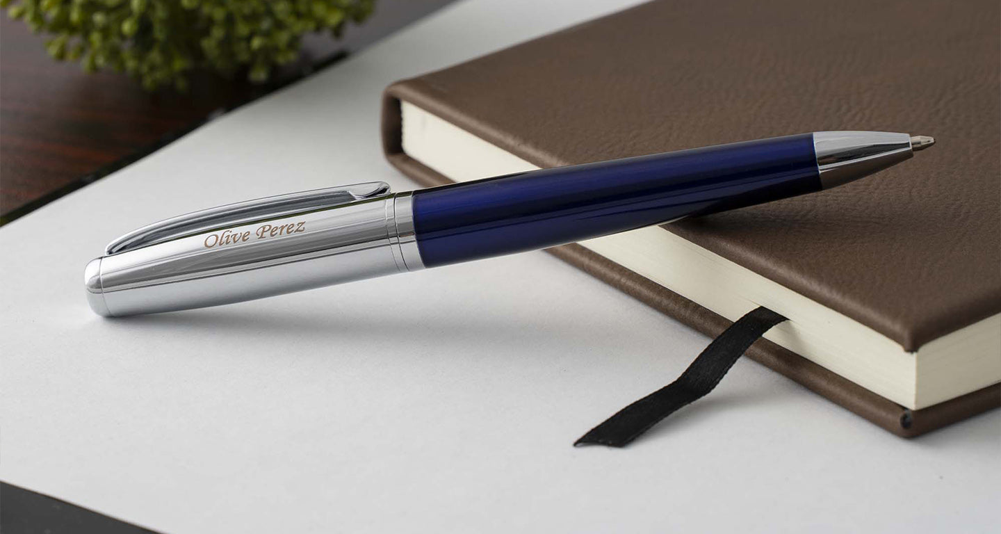 Blue Dayspring Abingdon Ballpoint leaning on brown journal.