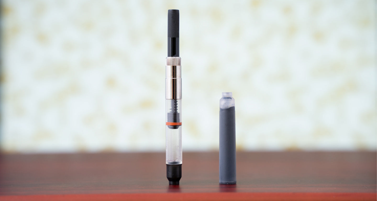 A fountain pen cartridge and converter sitting on a desk.