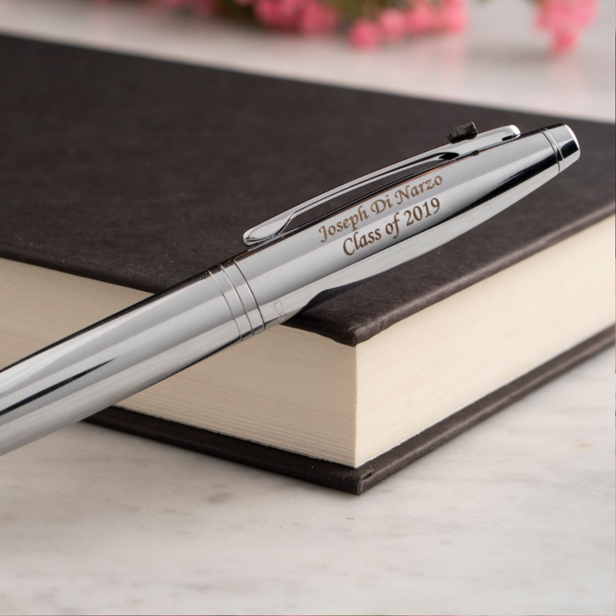 Engraved Calais Chrome Graduation Emblem Ballpoint sitting on a book 