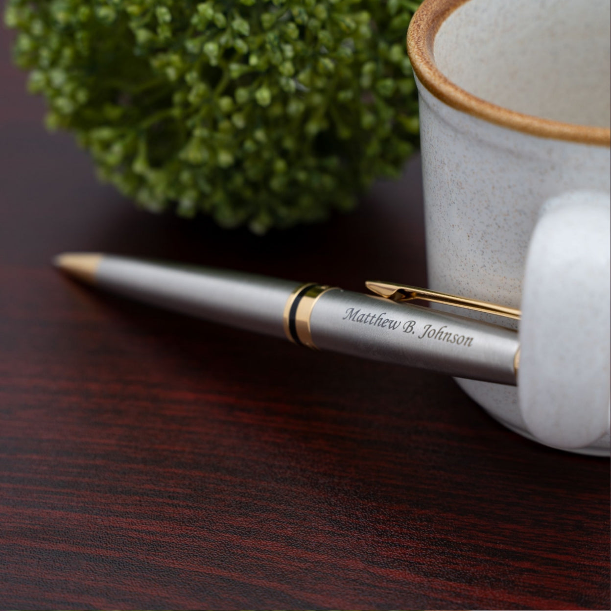 Engraved Expert Stainless Gold Trim Ballpoint displayed next to a coffee mug