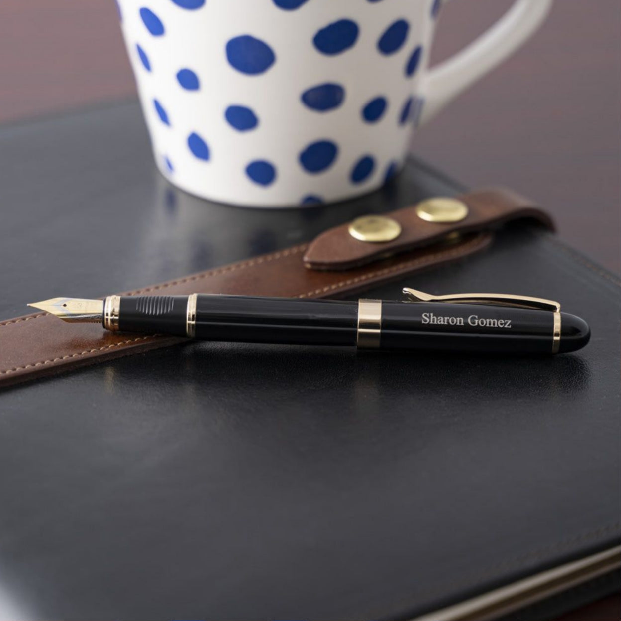 Engraved Alexandria Black Fountain Pen placed on journal next to coffee mug