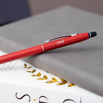 Engraved Click Crimson Red Ballpoint placed on top of two books 