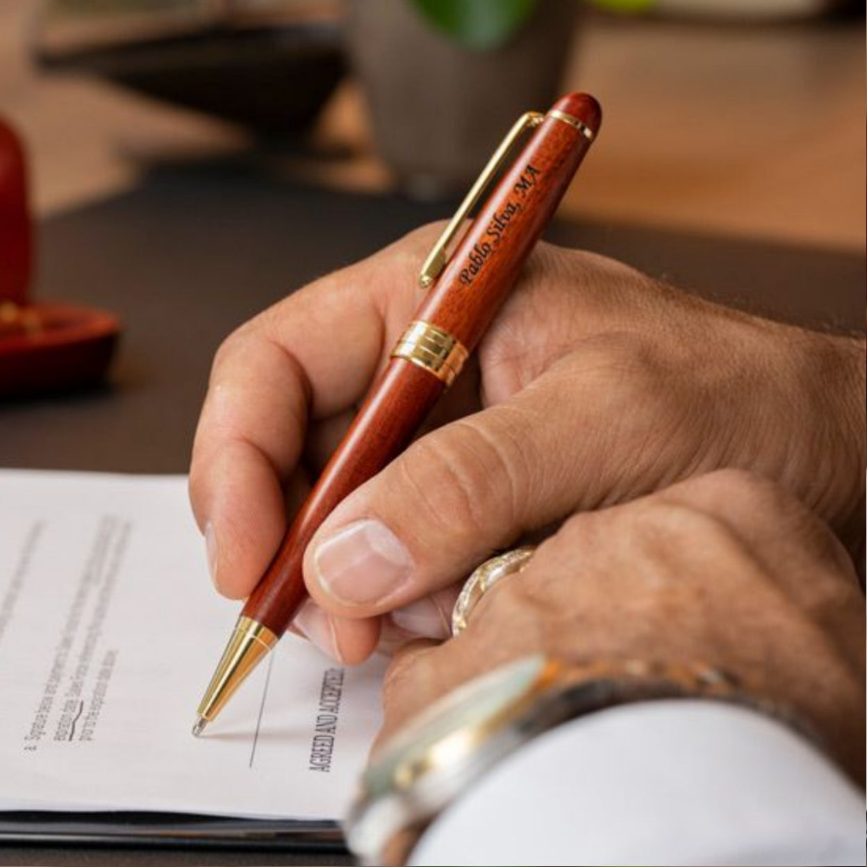 Man holding engraved Rosewood Ballpoint to sign document 