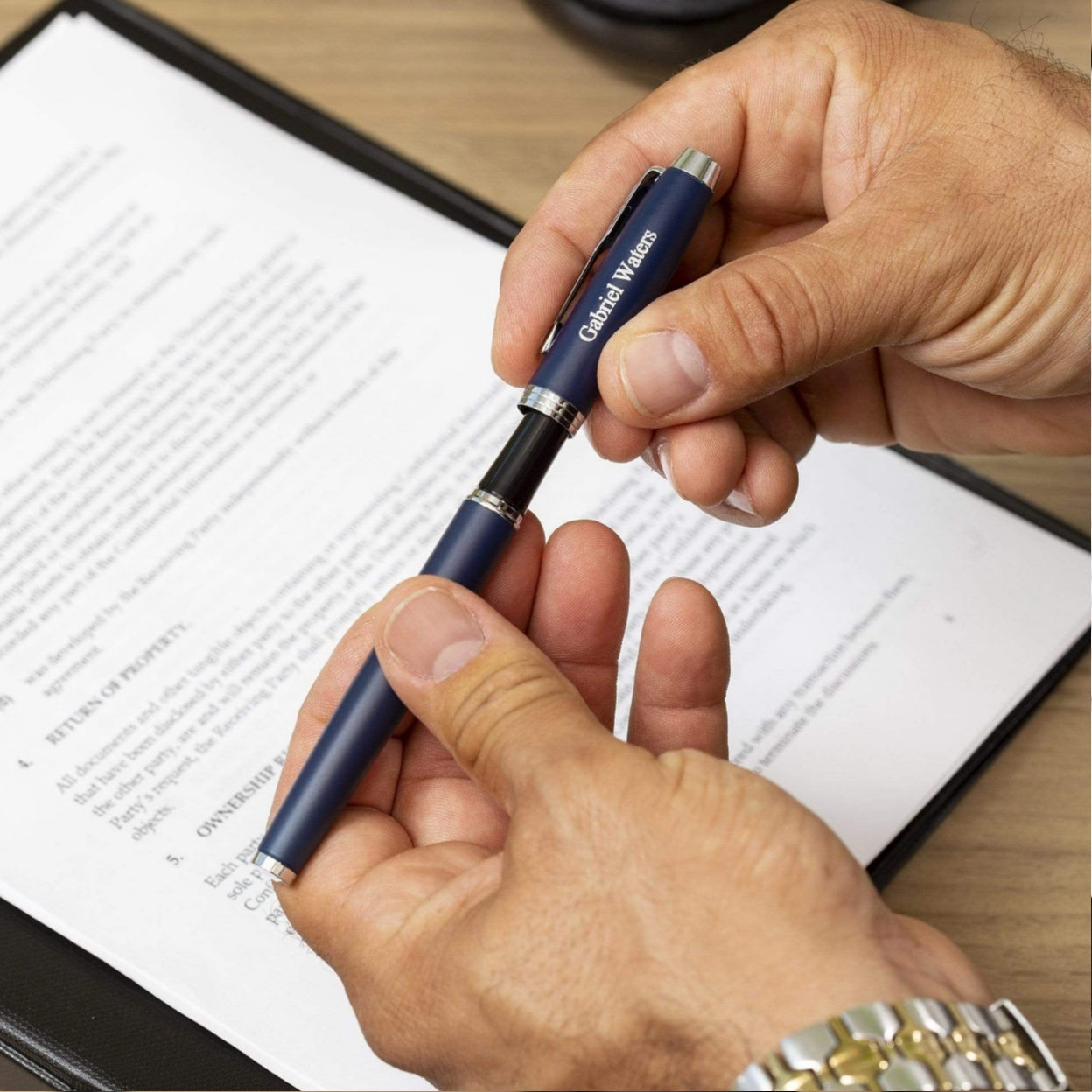 Man uncapping IM Blue Rollerball to sign document