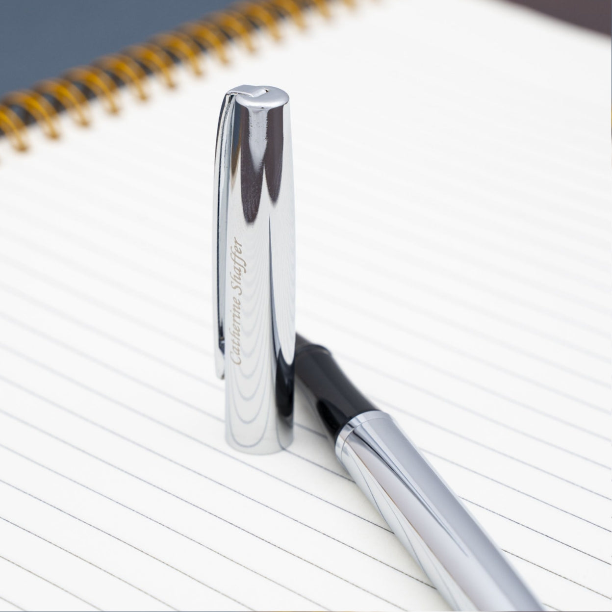 Engraved uncapped Richmond Chrome Rollerball placed on notebook