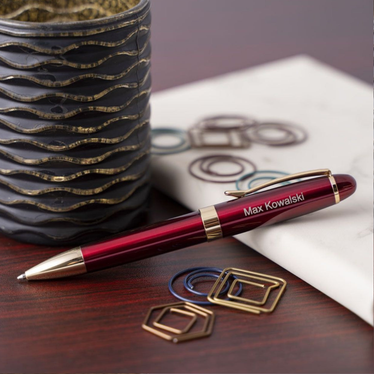 Engraved Alexandria Red Ballpoint displayed on journal next to cup and paper clips