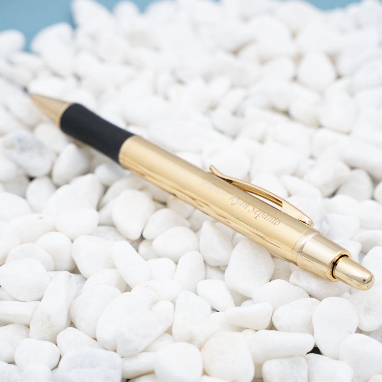 Engraved Monroe Gold Ballpoint Placed on top of white rocks