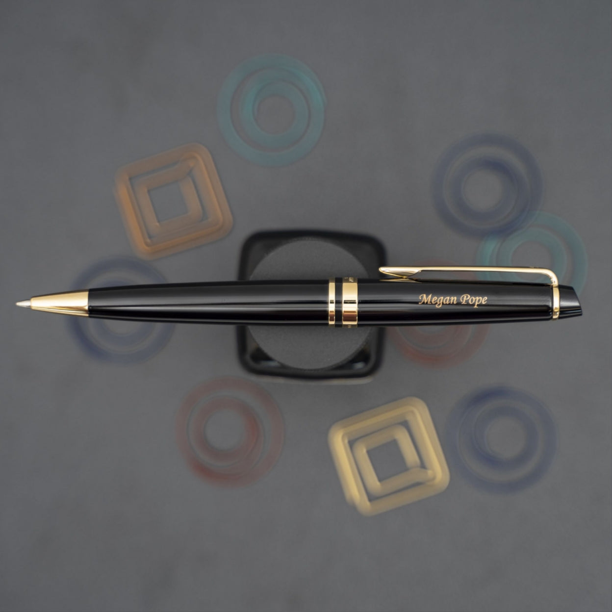 Engraved Expert Black Gold Trim Ballpoint on display next to paper clips