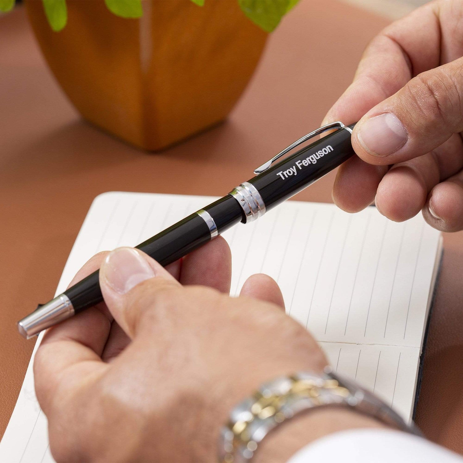 Man uncapping a Bailey Black Rollerball with a notebook