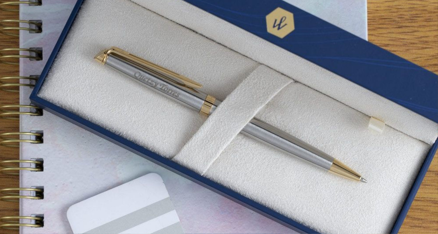Engraved Hemisphere Stainless Gold Ballpoint placed in box on top of notebook