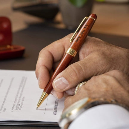 Man holding engraved Rosewood Ballpoint to sign a document