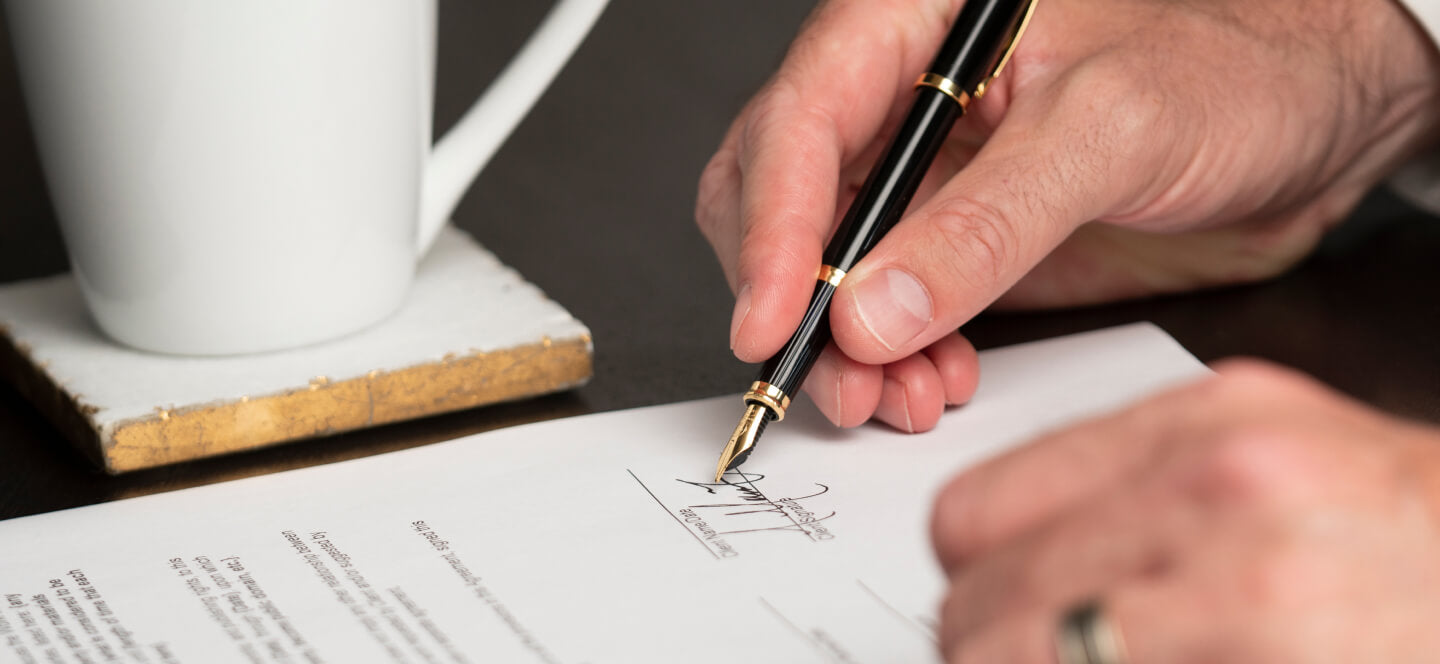 Person writing with fountain pen while drinking coffee