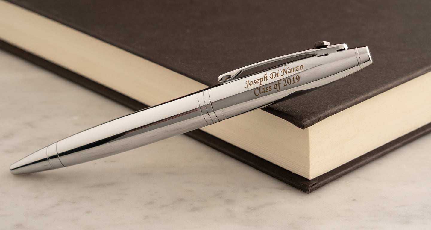 A chrome cross calais pen lying on a brown book with a personalized engraving