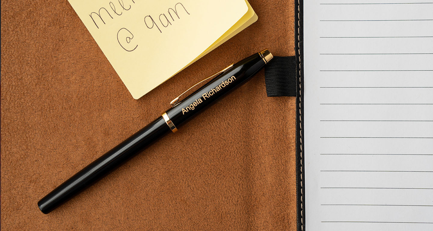 a black cross townsend rollerball lying on a notebook